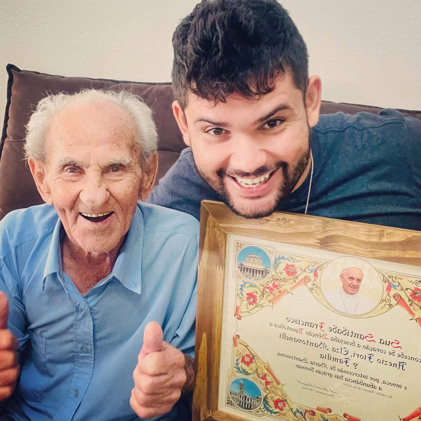 Caio e o Vovô Anésio com a bênção apostólica emoldurada