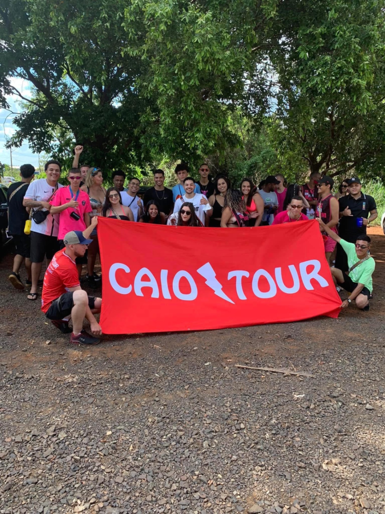 Excursão do Caio Tour reunida ao ar livre segurando a faixa